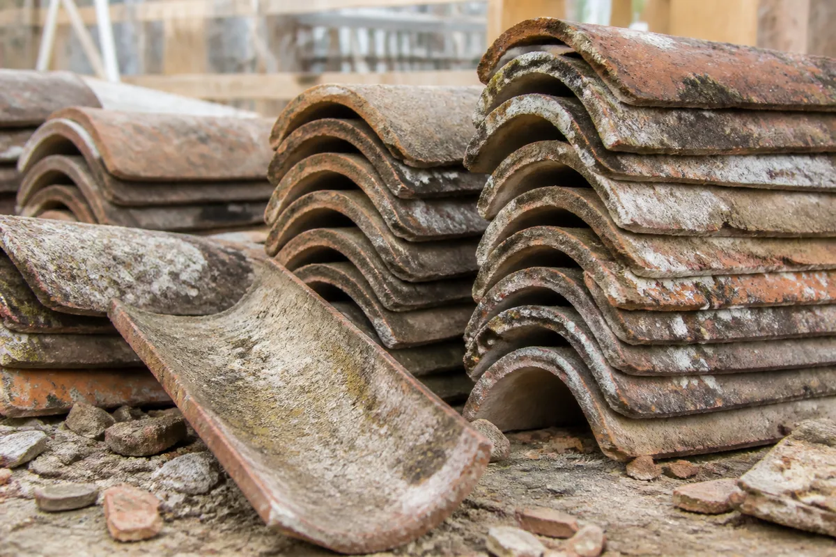 Tuiles canal anciennes triées et empilées sur un chantier de couverture